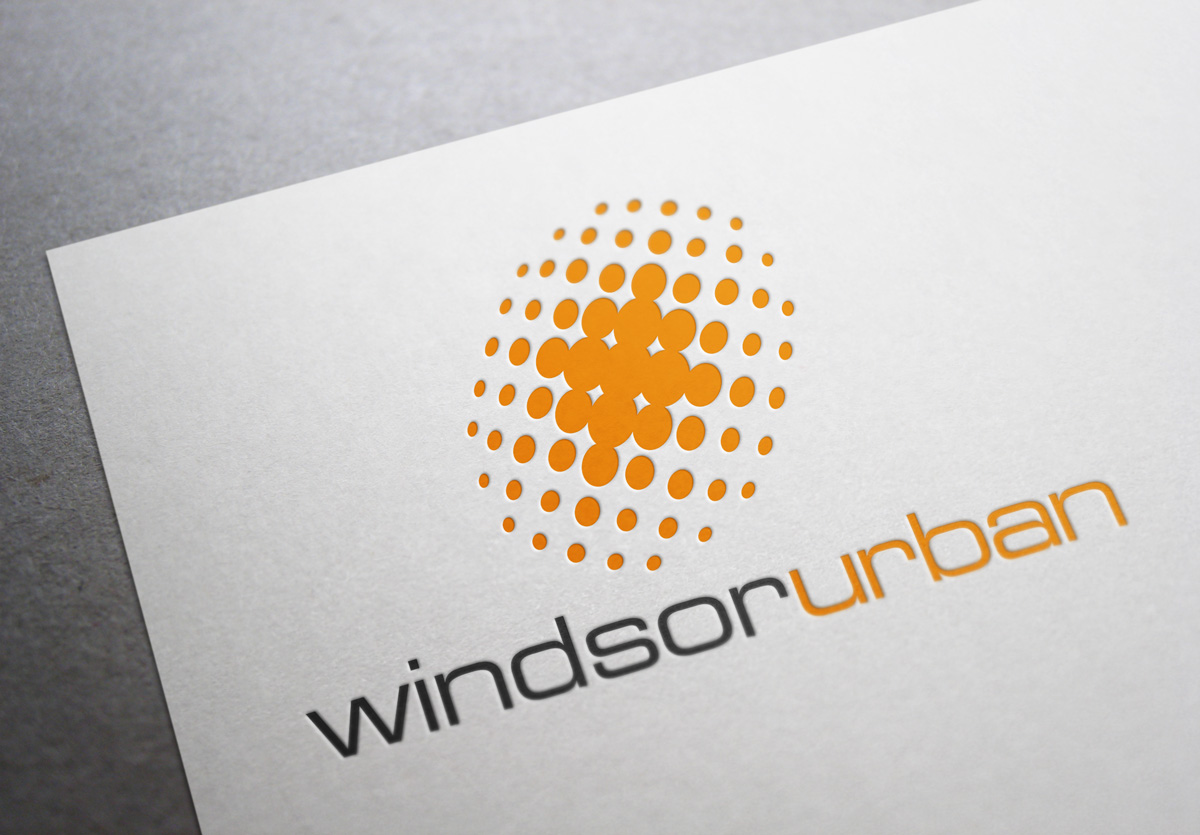Windsor Urban symbol and type logo and trademark, two colours bright orange and dark grey on white. The symbol is a stylized pool of light drawn in coarse halftone dots that form a radial glow from the centre out within an implied slanted oval shape. Windsor Urban name is set as a unit, in clean extended sans-serif Eurostile font, the words differentiated by a colour change from dark grey to orange. Company rename and rebrand. Brands for New Zealand companies, Christchurch New Zealand.