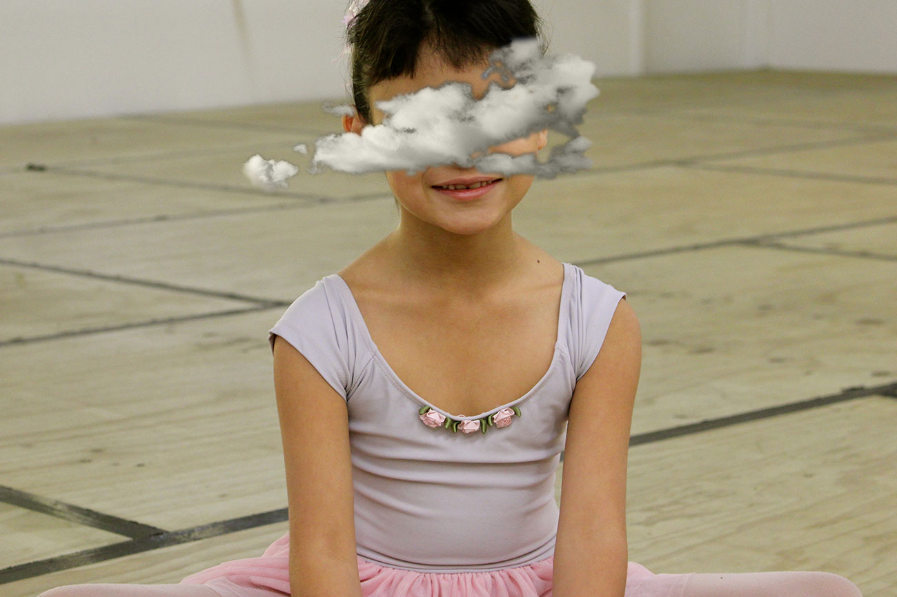 Young ballet dancer seated on studio floor.