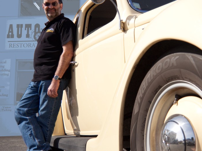 Auto Restorations skilled workforce informal portrait of Allan Wylie, managing director, leaning against his 1938 Ford roadster.