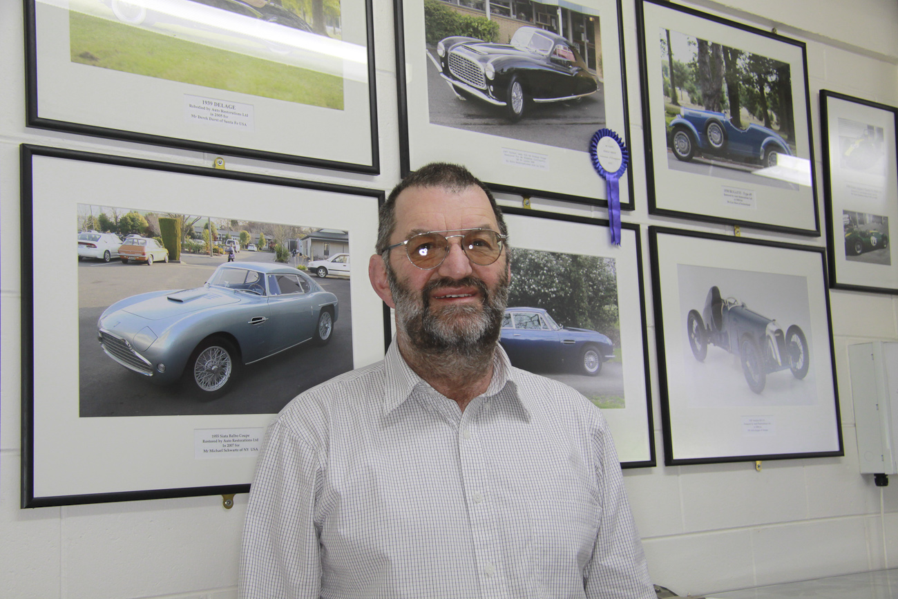 Concours award winners form the background of this informal portrait of Allan Wylie, managing director, reception area, Auto Restorations.
