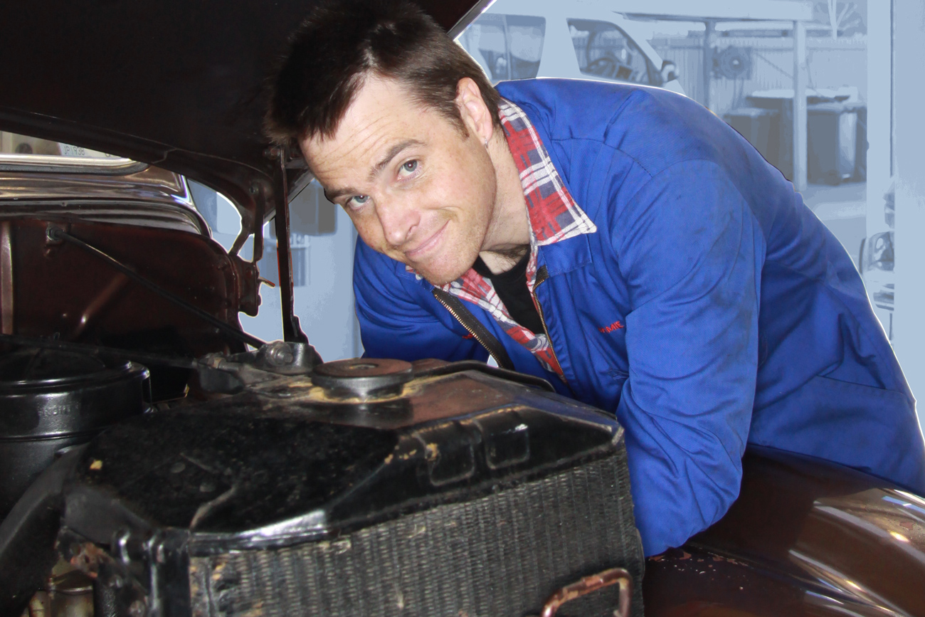 Jamie Graham making auto electrical repairs under the bonnet of a 1930s classic American V8 in the Machine Shop at Auto Restorations.