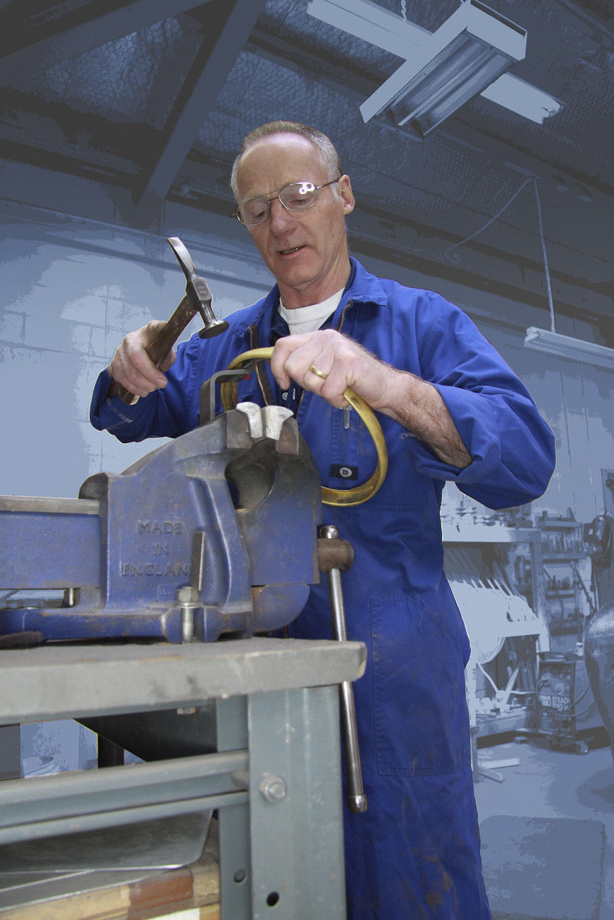 Mike Brosnan hand forms a bespoke brass headlight trim, prior to it being chromed to finish, in the Panel Shop at Auto Restorations.