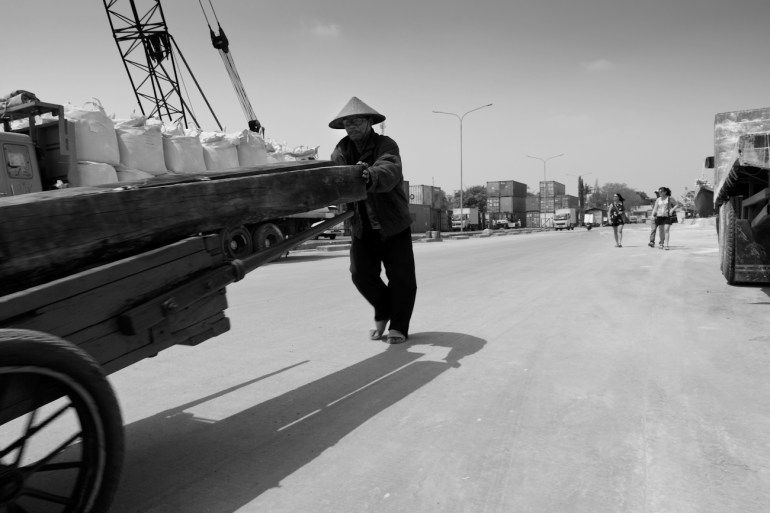 A Coolie port worker loading sawn logs on a hand pushed cart at the port of Sunda Kelapa, Jakarta, Indonesia.