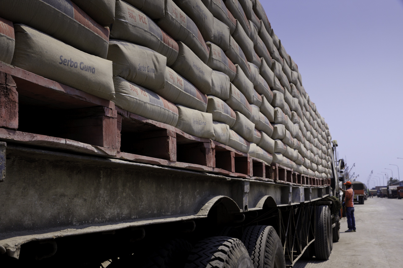 Freight trucks lined up with truckloads of cement, alongside magnificent Makassar schooners called Pinisi at the port of Sunda Kelapa, Jakarta, Indonesia.