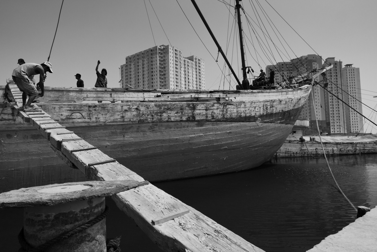 A typical wooden cargo boat gangplank and coolies. These magnificent Makassar schooners called Pinisi are an important means of transporting goods to and from the outer islands of Indonesia.