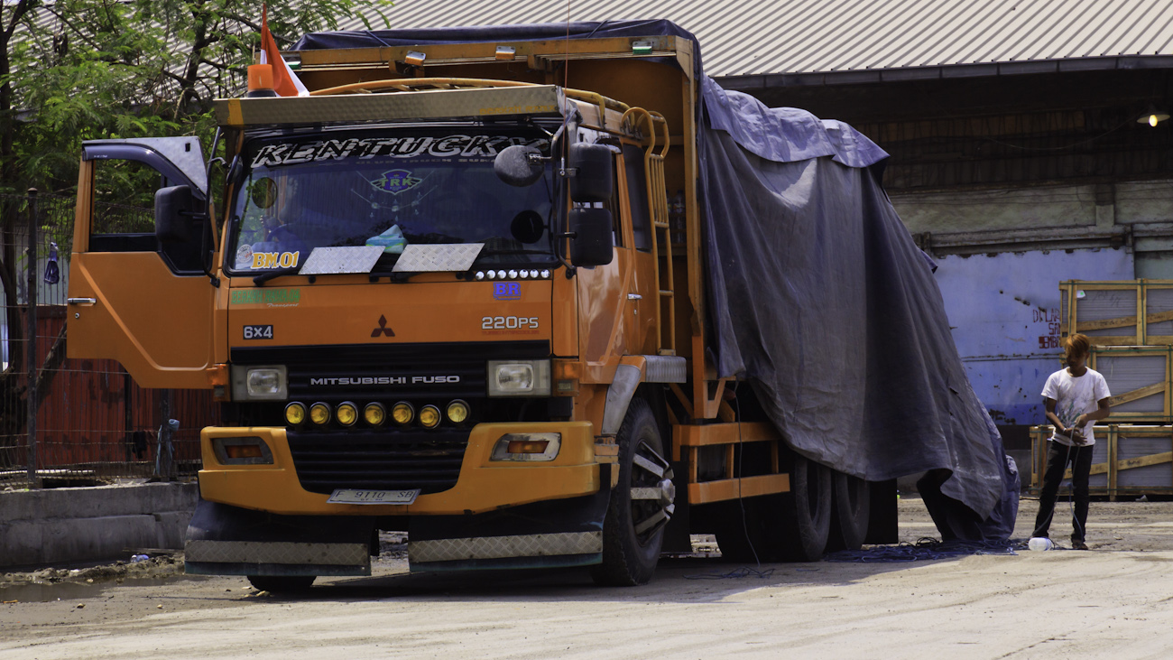 Driver of a freight truck named ‘Kentucky’ coils rope lined up at the port of Sunda Kelapa, Jakarta, Indonesia.