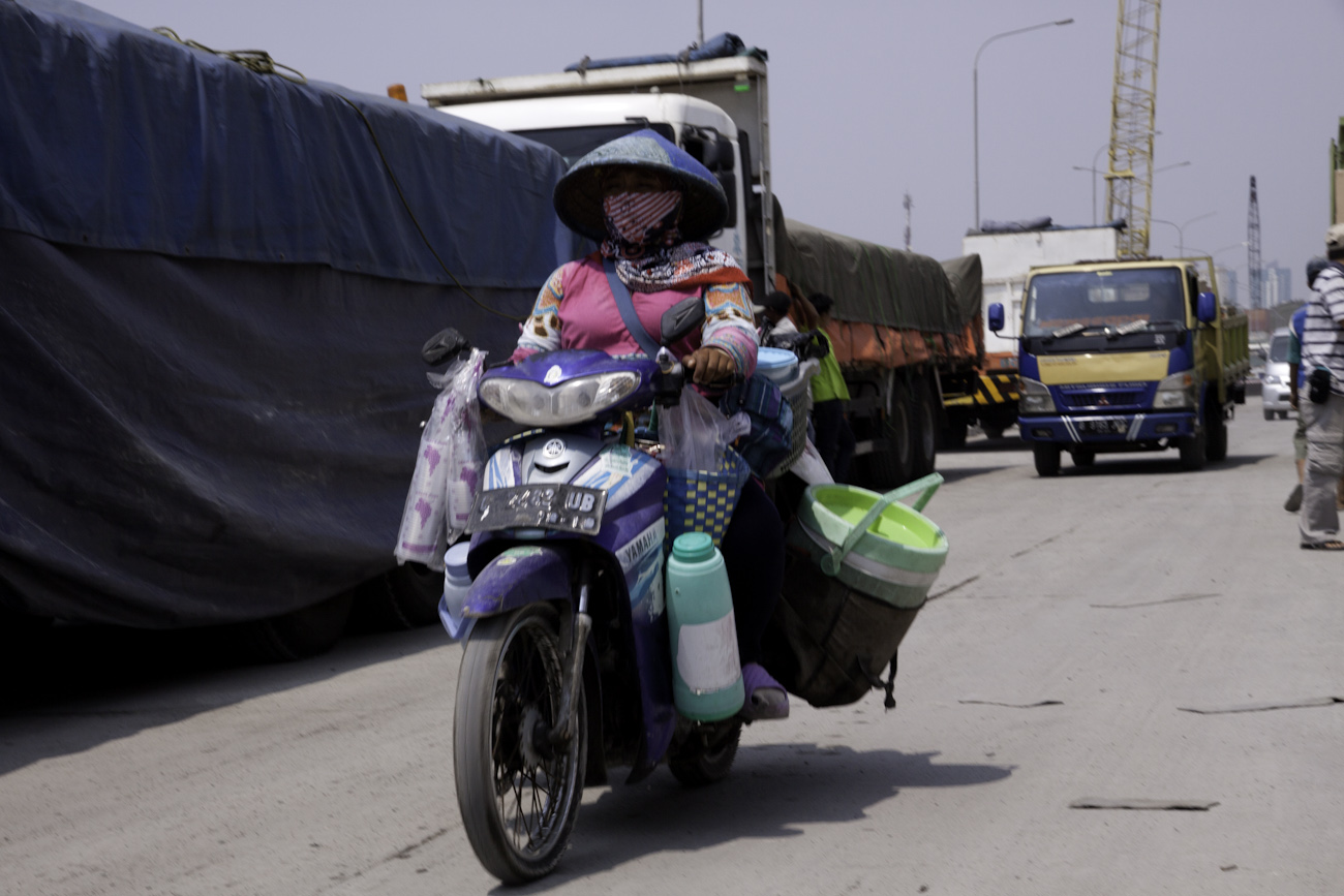 Mobile cafeteria on a scooter motors down the wharf at the old port of Sunda Kelapa, Jakarta, Indonesia.