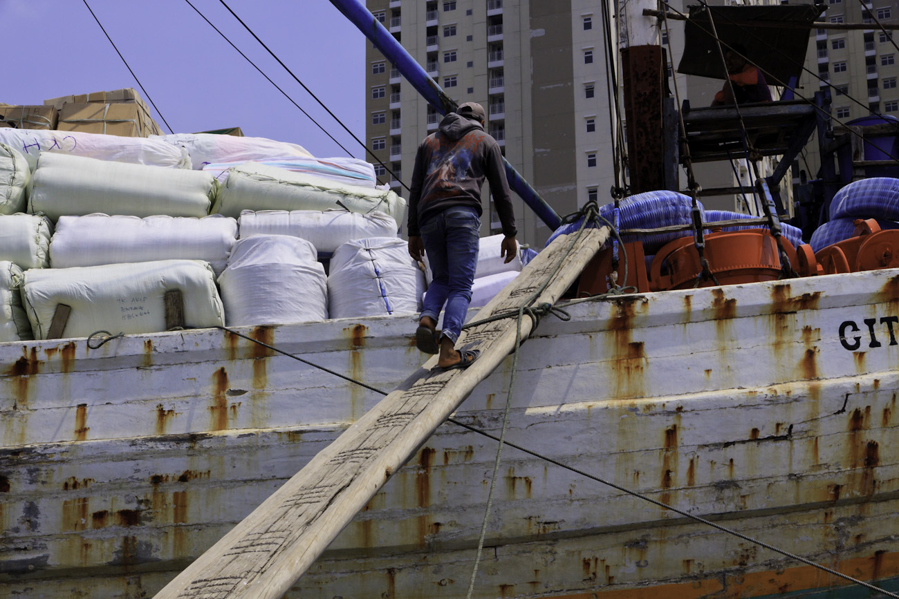 A Coolie walks up the gangplank to board a Pinisi at the port of Sunda Kelapa, Jakarta, Indonesia.