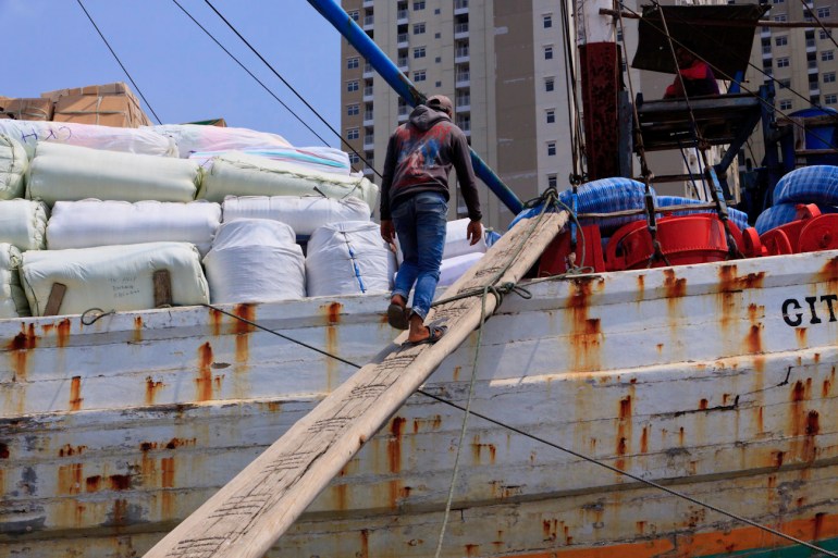 A Coolie walks up the gangplank to board a Pinisi at the port of Sunda Kelapa, Jakarta, Indonesia.