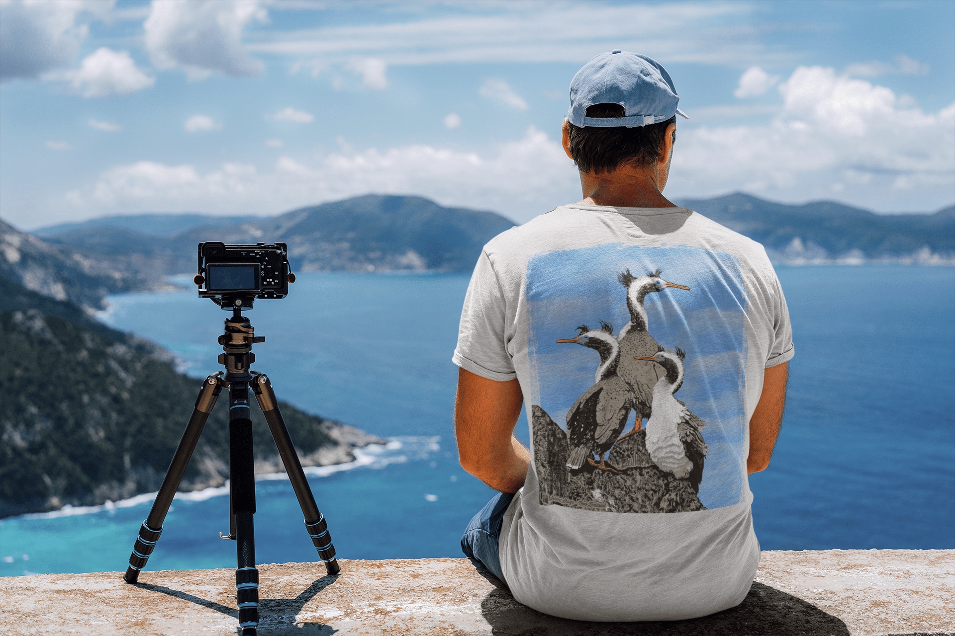 Back view of a man enjoying the landscape wearing a silver-grey spotted shags two-sided t-shirt.