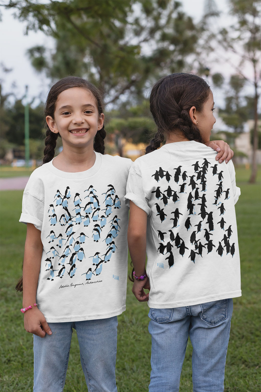 twin girls wearing Adelie penguins t-shirts showing front and back print in a park