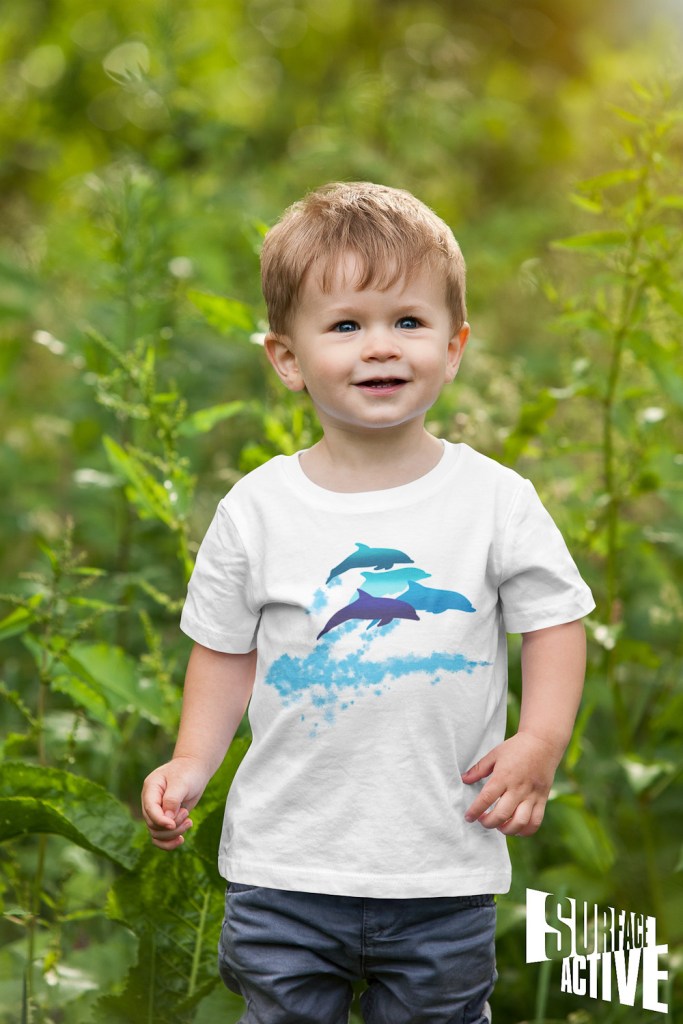 A toddler wearing a dolphins leaping New Zealand t-shirt and walking in nature.