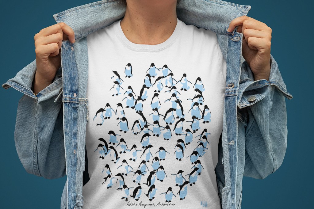 A woman showing off her Adelie penguins Antarctica t-shirt under her denim jacket.