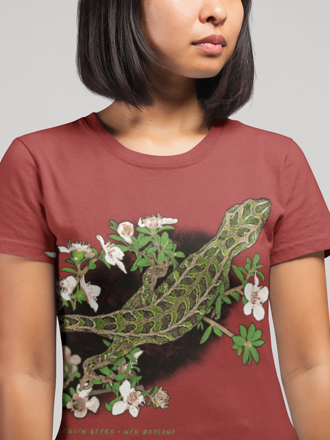 Close-up of a woman's face wearing a t-shirt with a wrap-around print of the Harlequin Gecko's pattern, highlighting the detailed design.