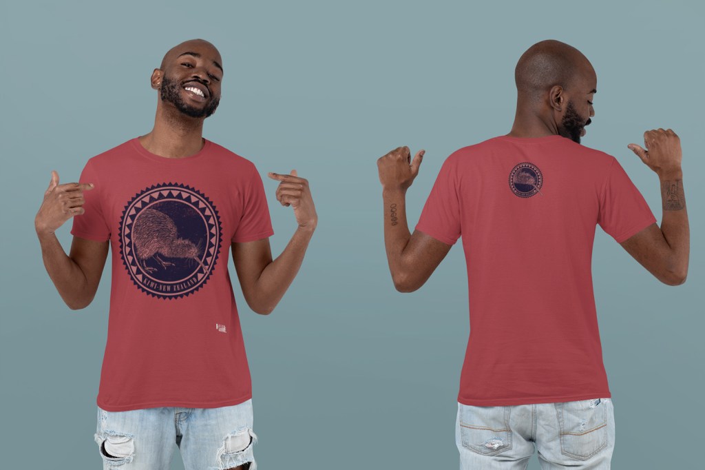 Young man modeling a red t-shirt with a large front print and smaller back badge of the Kiwi Roundel design, photographed in a studio.