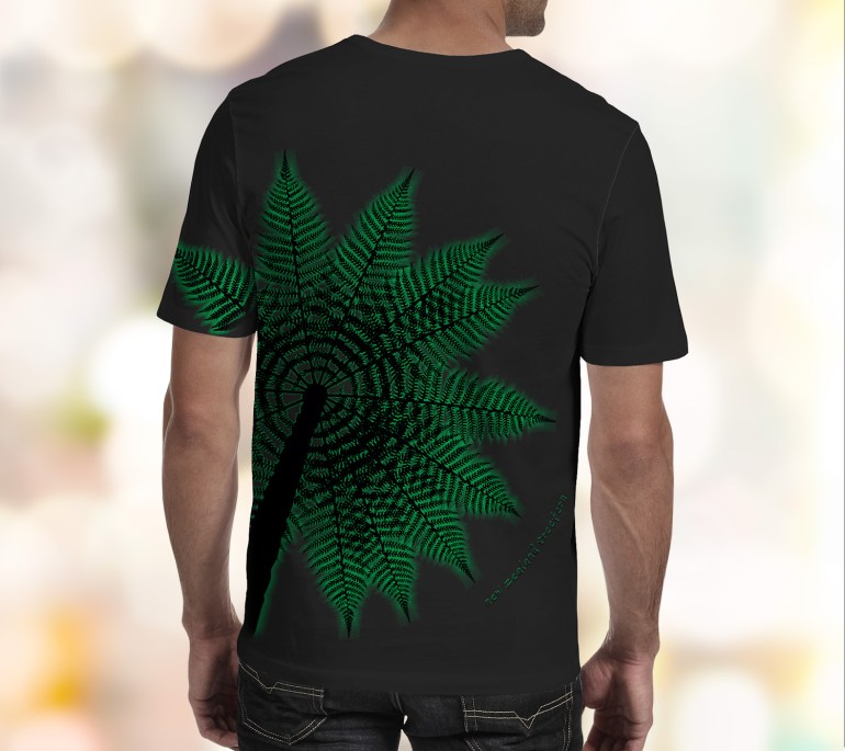 A black Surface Active all-over printed Treefern New Zealand t-shirt worn by a young man with his back to the camera in the studio.