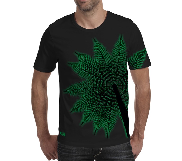 A black Surface Active all-over printed Treefern New Zealand t-shirt worn by a young man facing the camera in the studio.