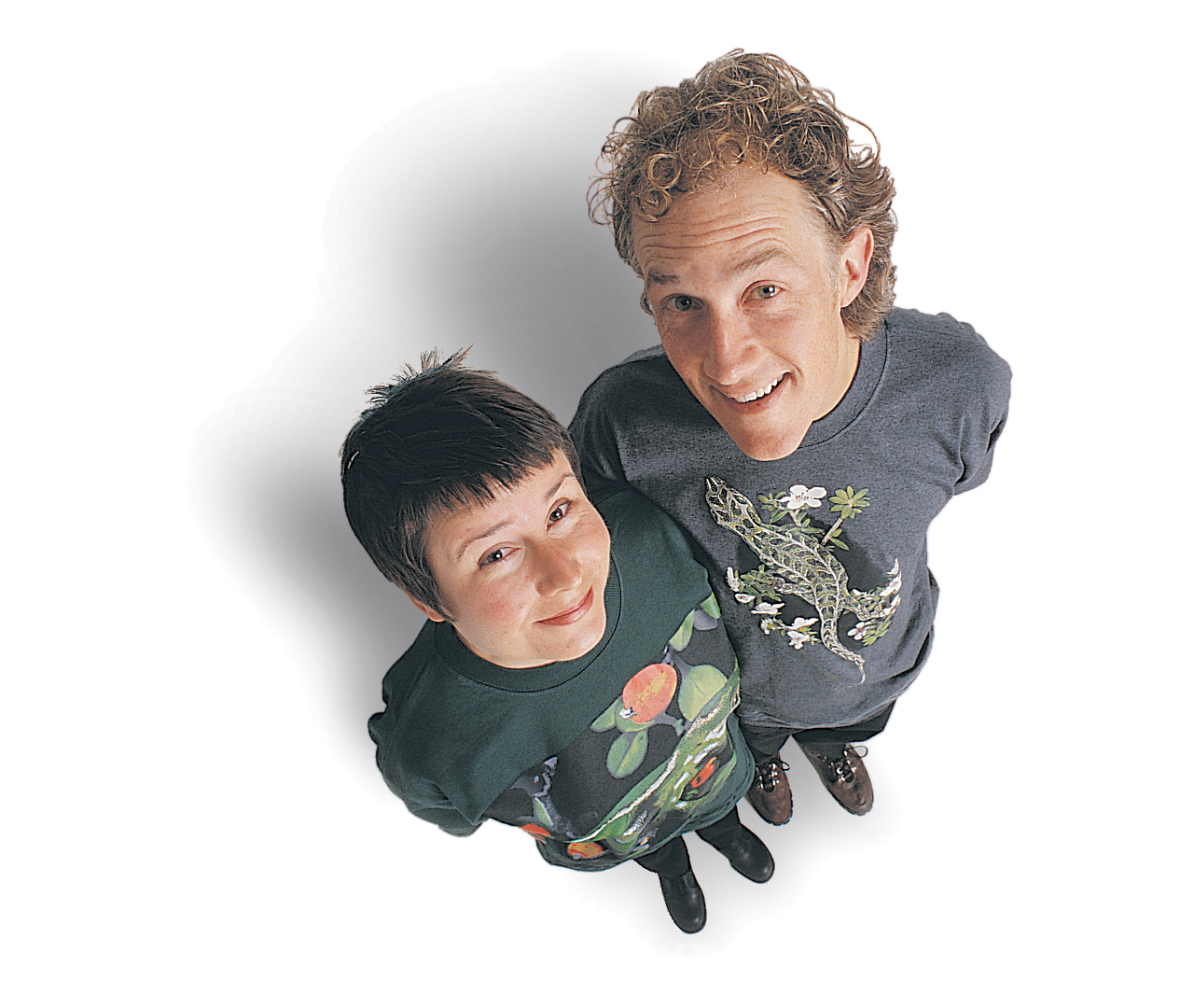 Birds-eye view portrait of Surface Active t-shirt’s design pARTners, Chrissie Terpstra and Shaun Waugh, wearing Harlequin and Jewelled Gecko tees, against a white background, shot in a studio in 1996.