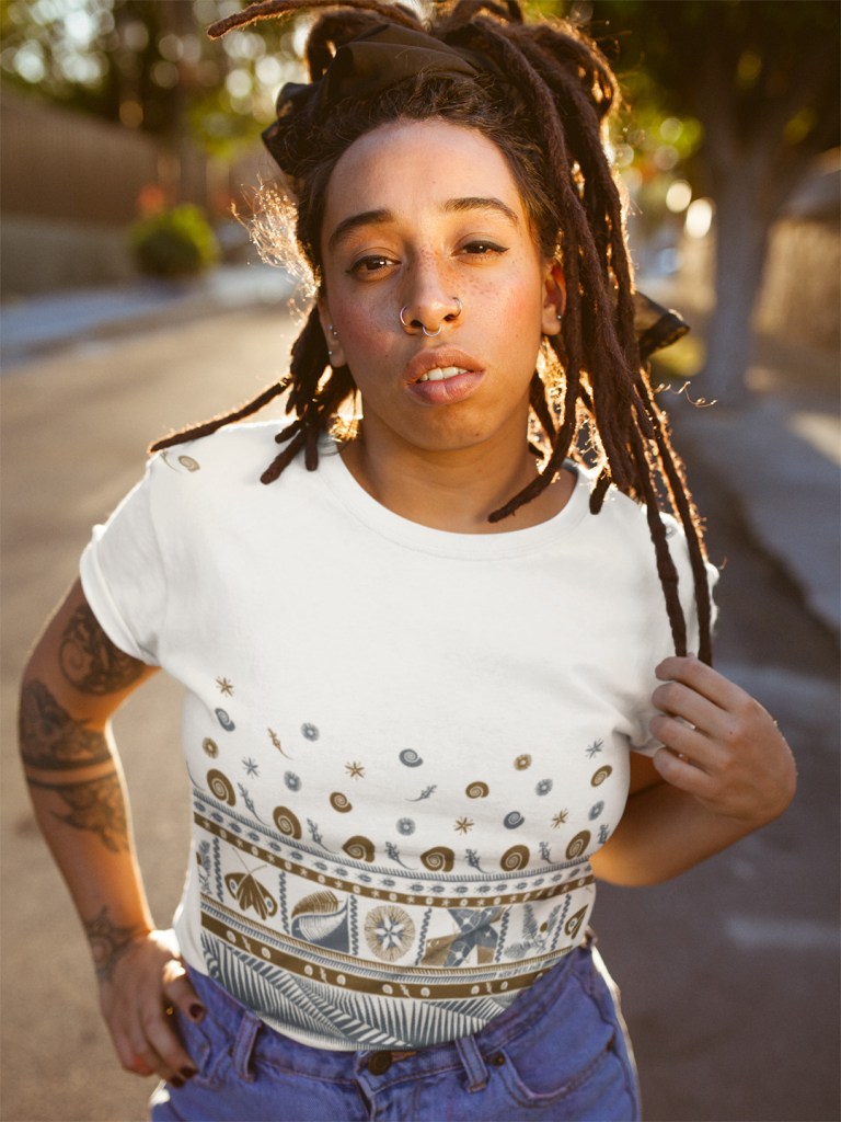 A woman with dreadlocks wearing a white Surface Active tapa t-shirt.