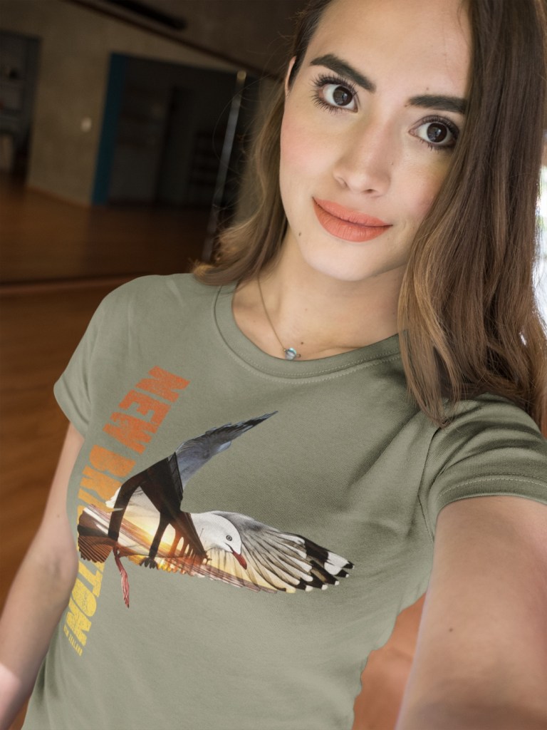 A beautiful woman taking a selfie while wearing a Surface Active red-billed gull, New Brighton t-shirt.