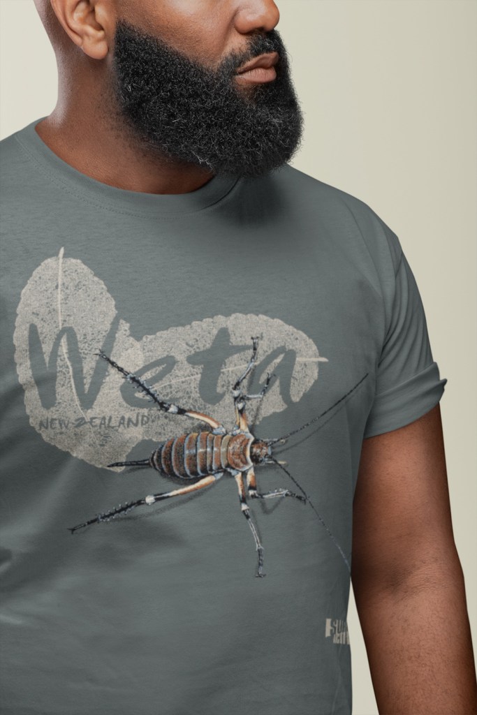 Close-up of a man with a thick beard wearing a grey Surface Active weta New Zealand t-shirt.