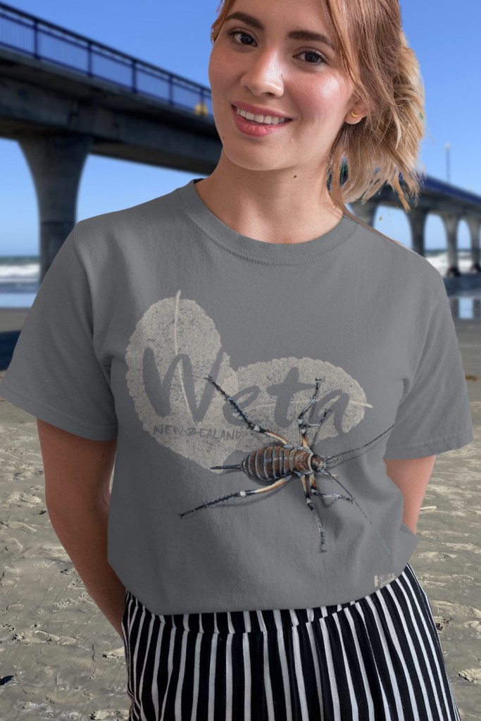 A pretty young woman wearing a Surface Active weta New Zealand t-shirt beside New Brighton pier.