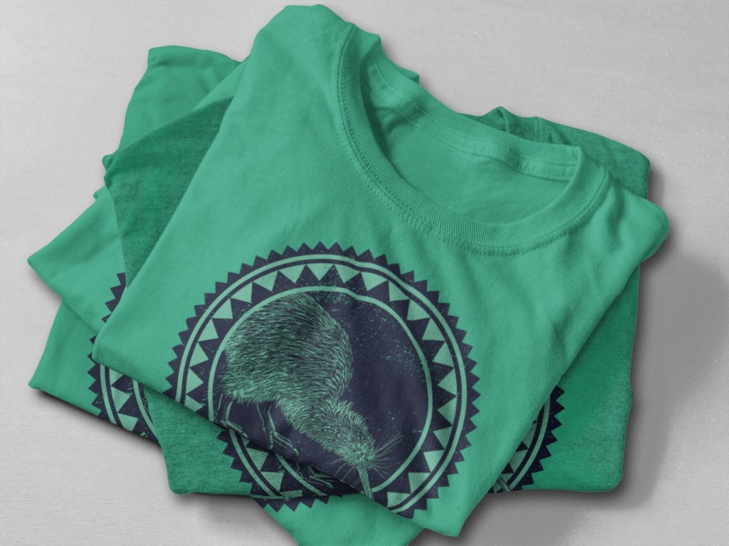 A close-up of a stack of Kelly green Surface Active Kiwi t-shirts.
