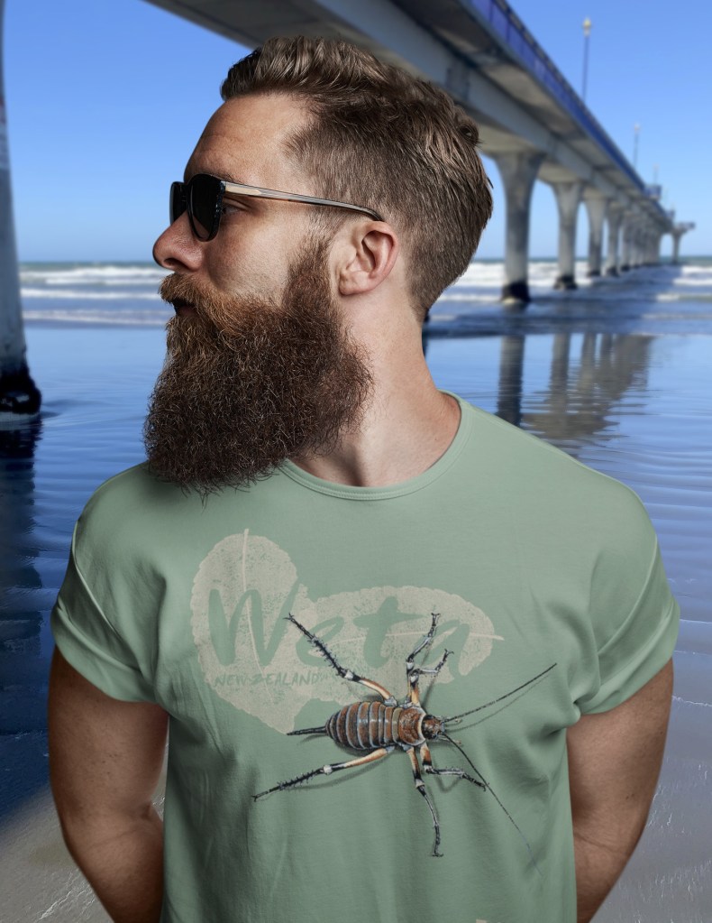 Close-up of a sage green Surface Active giant weta t-shirt beside New Brighton pier.