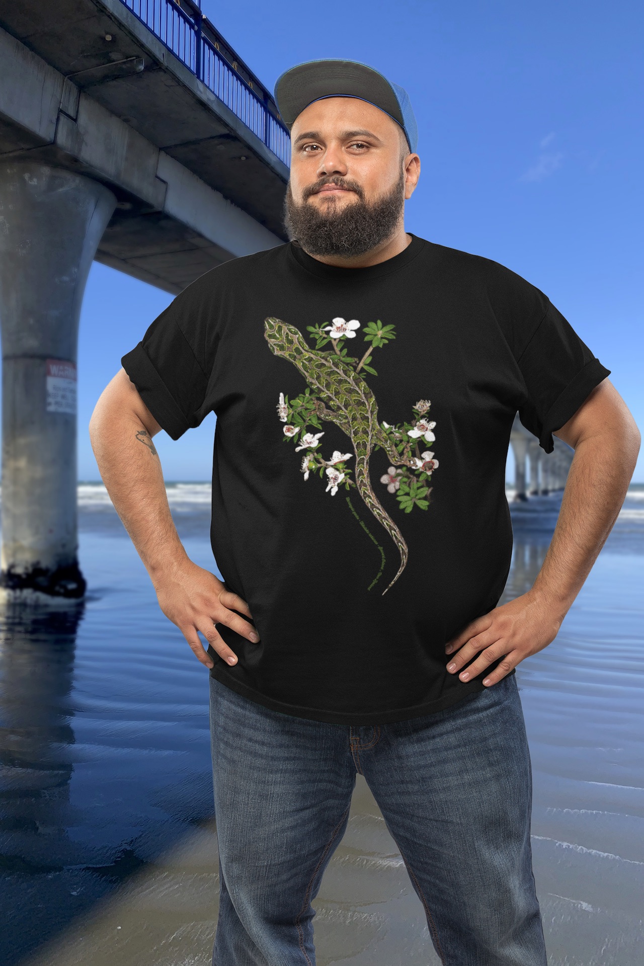 Man wearing a harlequin gecko t-shirt standing beside New Brighton Pier.