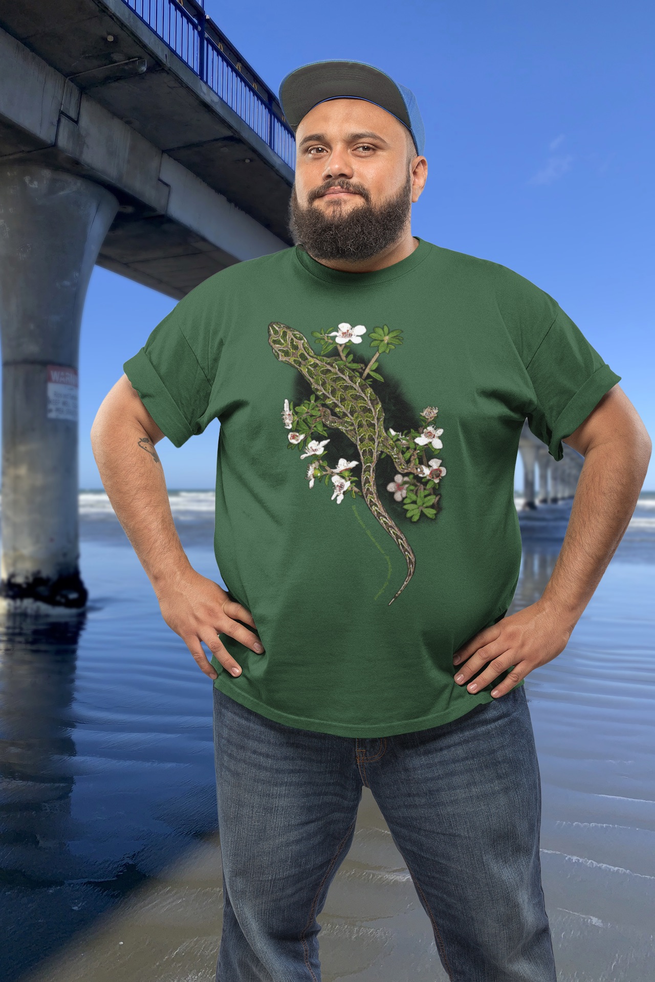 Man wearing a harlequin gecko t-shirt standing beside New Brighton Pier.