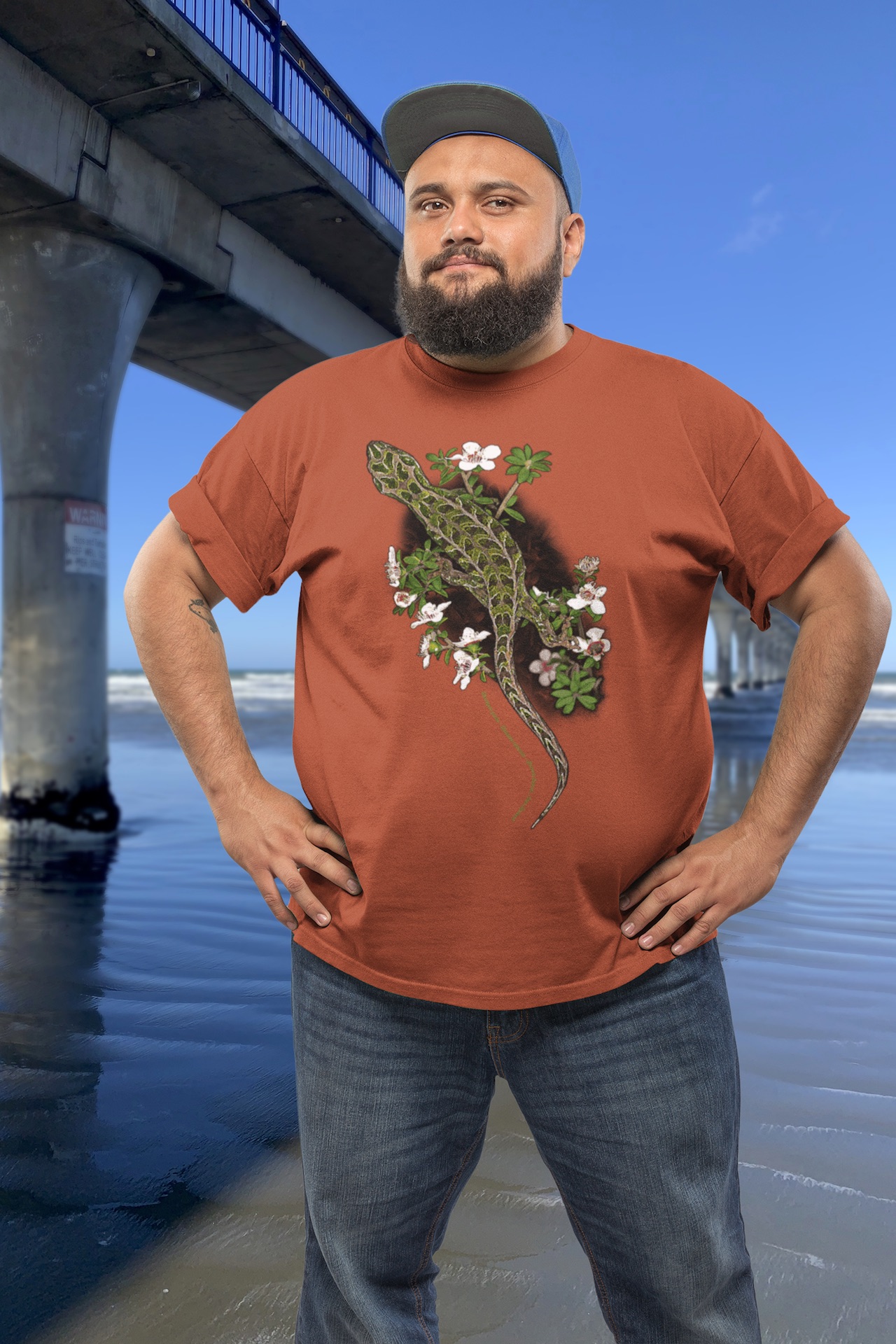 Man wearing a harlequin gecko t-shirt standing beside New Brighton Pier.