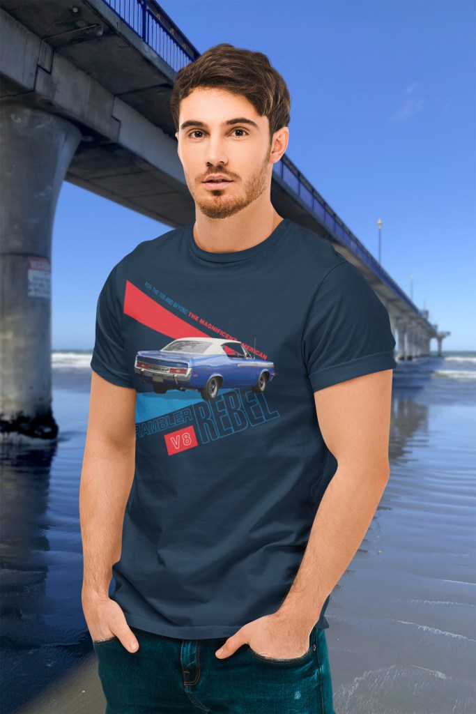 Man wearing a navy blue t-shirt with a vibrant 1970 Rambler Rebel SST graphic beside New Brighton Pier, which extends eastward like a concrete freeway onramp.