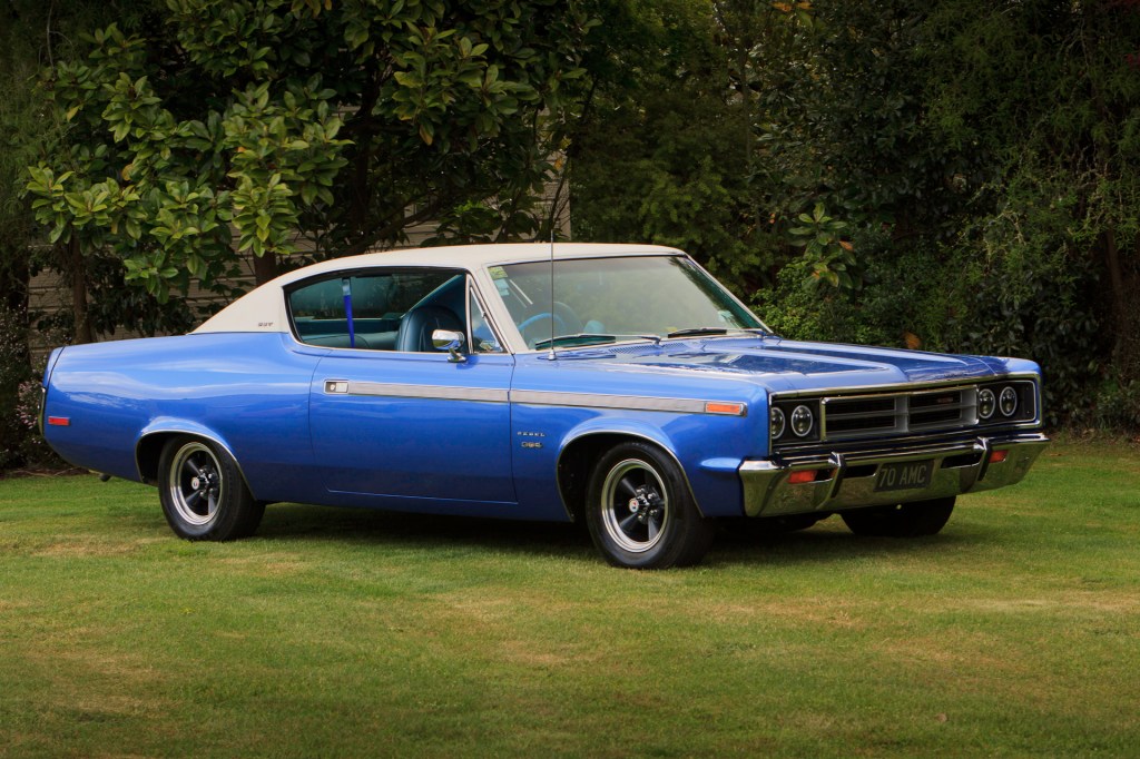 Royal blue 1970 Rambler Rebel SST viewed from the driver's side with an angle towards the front, highlighting the hood, grille, and bumper.