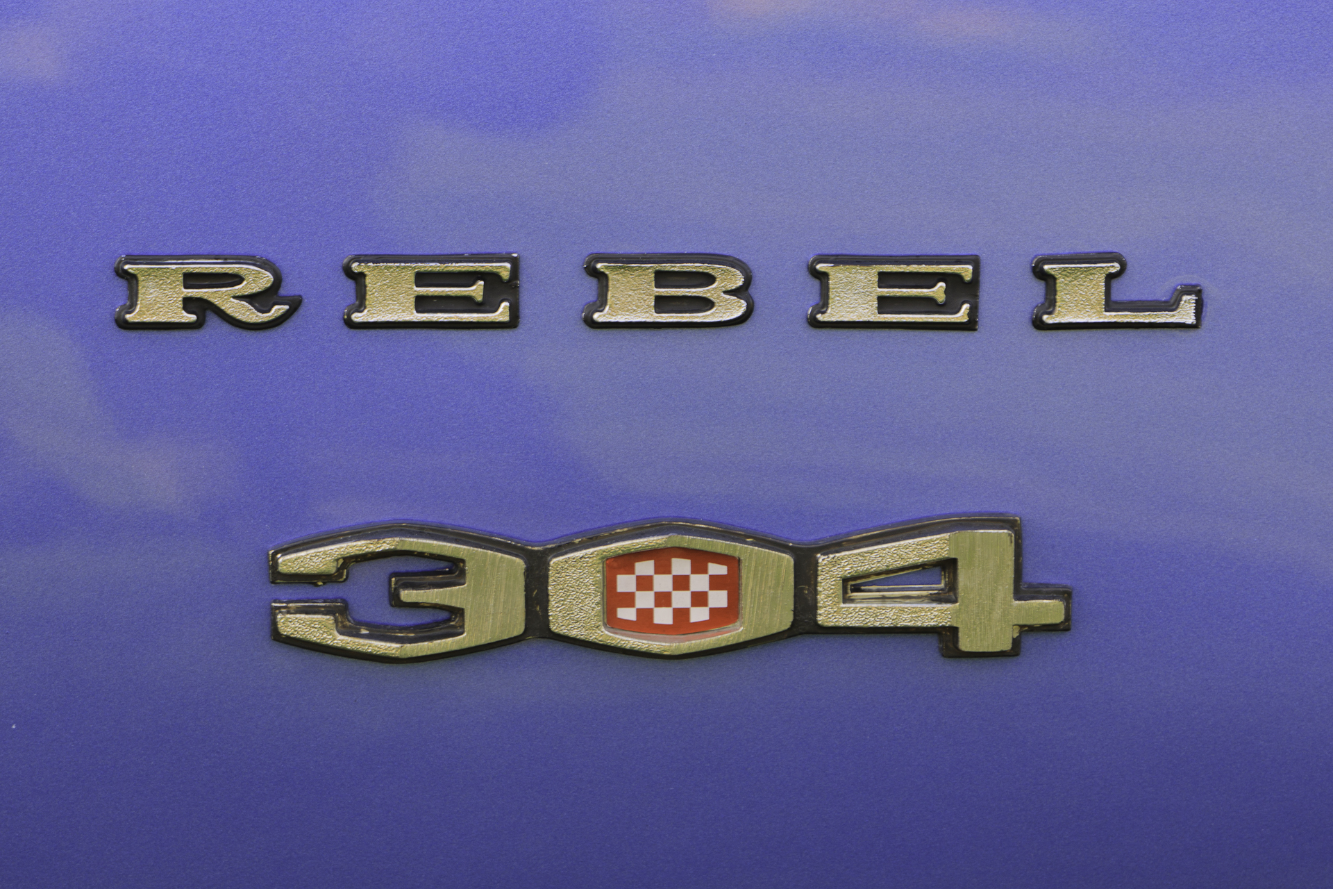 Close-up of 'Rebel - 304' badge on the royal blue fender of a restored 1970 Rambler Rebel SST.