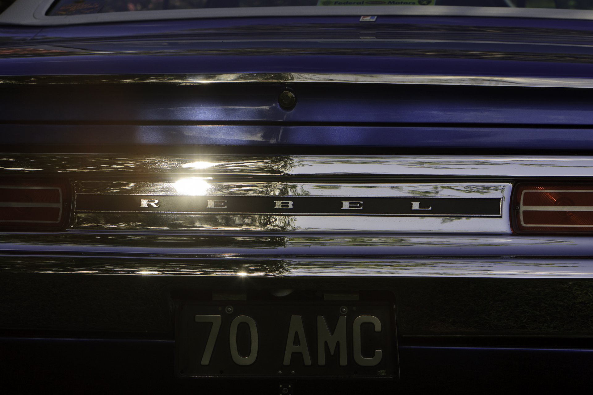 Close-up rear view of a restored royal blue 1970 Rambler Rebel SST, photographed from a low angle highlighting the taillights and chrome details.
