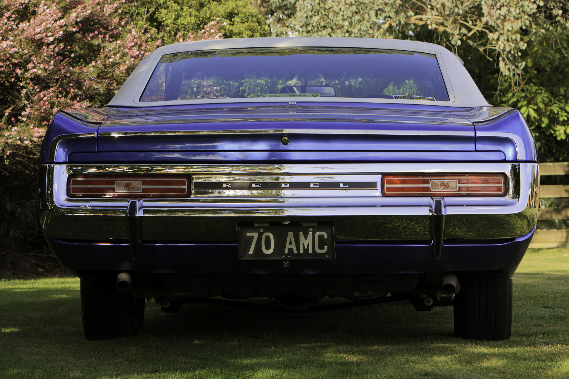 Low-angle rear view of a fully restored 1970 Rambler Rebel SST in royal blue, showcasing its chrome details and classic taillights.