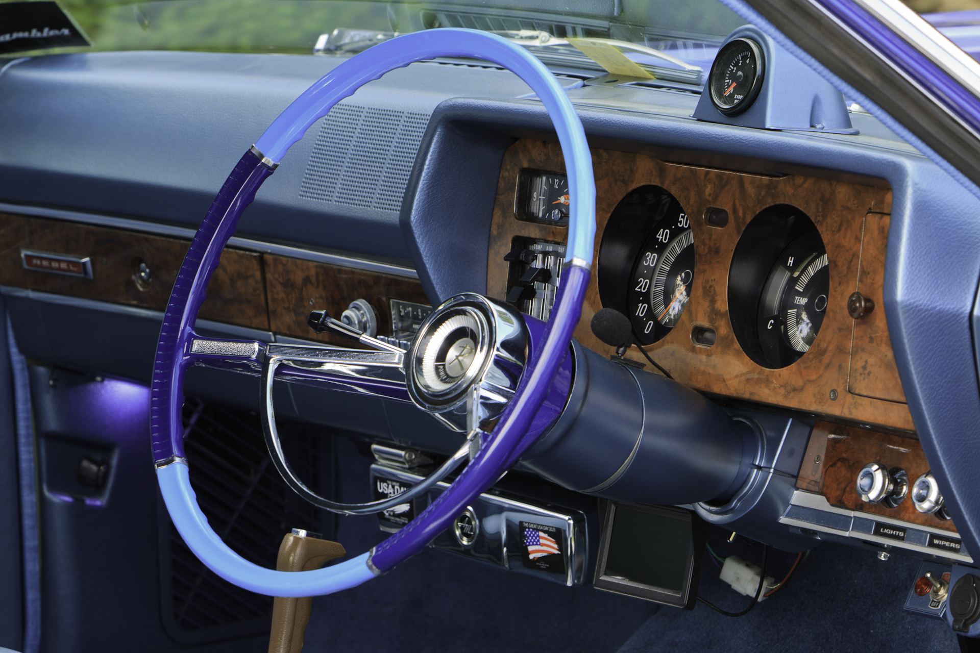 Interior view of a 1970 Rambler Rebel SST, showcasing the restored walnut dashboard, classic gauges, and two-tone steering wheel.