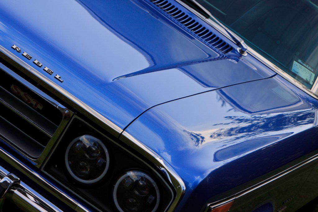 Close-up detail of a royal blue 1970 Rambler Rebel SST, showcasing chrome and bodywork in an abstract, artistic manner