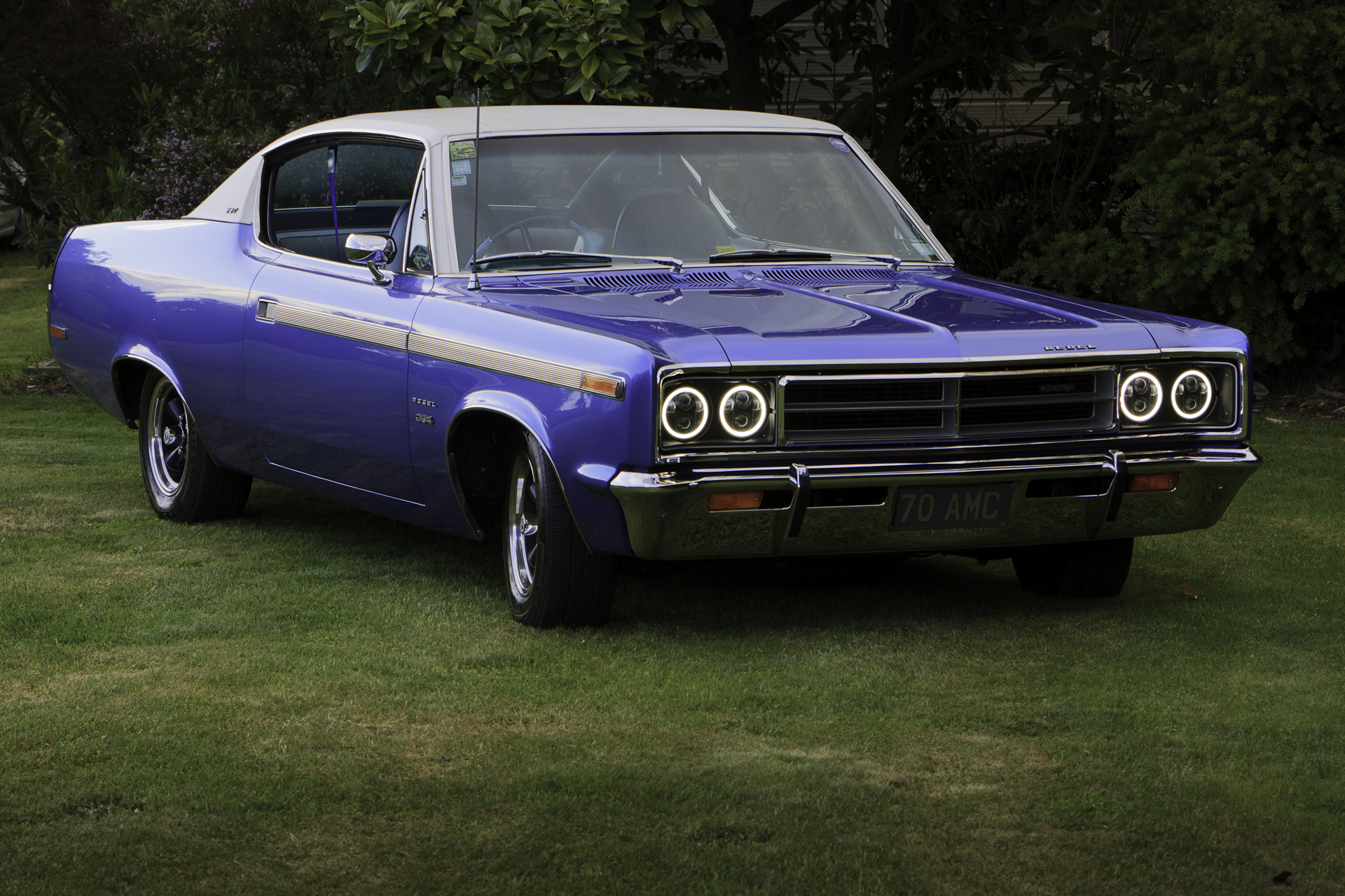 Three-quarter front view of a restored 1970 Rambler Rebel SST in royal blue, featuring chrome details and vinyl roof.