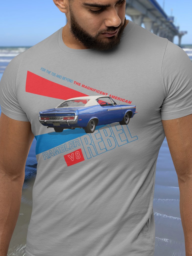 Bearded man in grey marle t-shirt with 1970 Rebel SST design stands beside New Brighton Pier, pointing symbolically towards Chile.