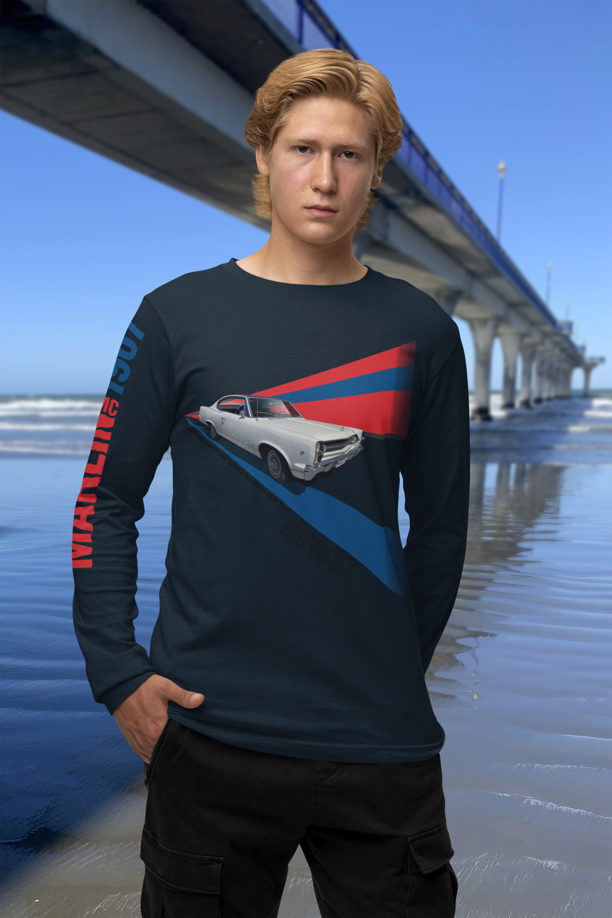 Man wearing a navy blue AMC Marlin long-sleeve t-shirt beside New Brighton's concrete pier under a clear blue sky.