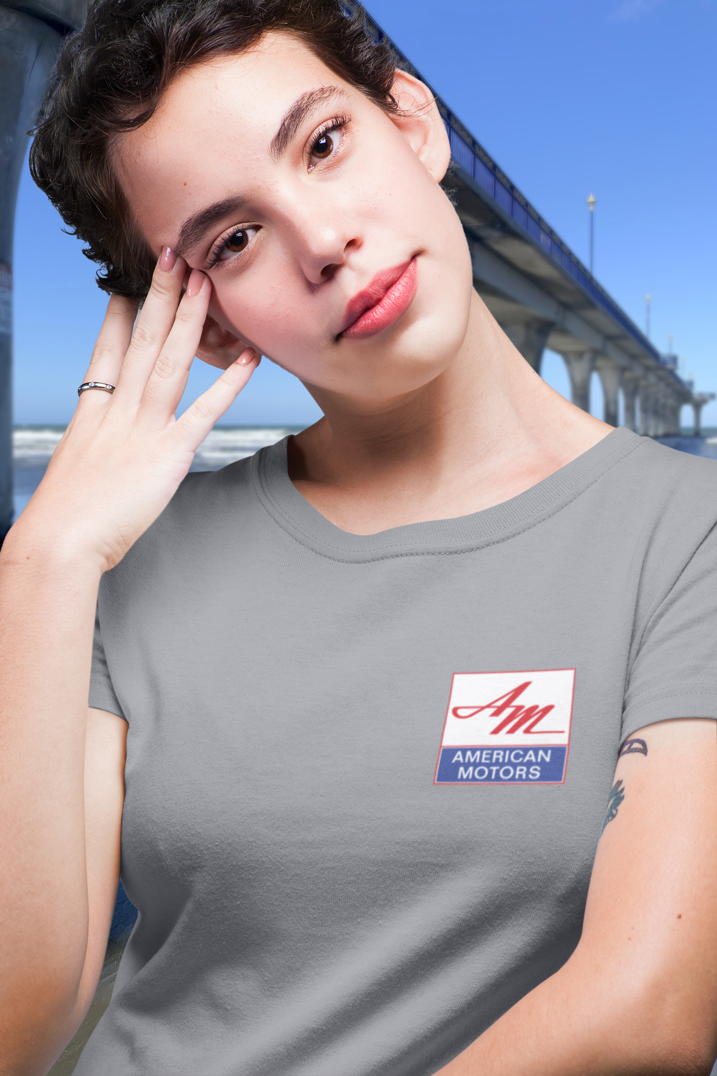 Woman in grey marle t-shirt with 1967 AMC Marlin design, featuring a square AMC logo badge on her chest.