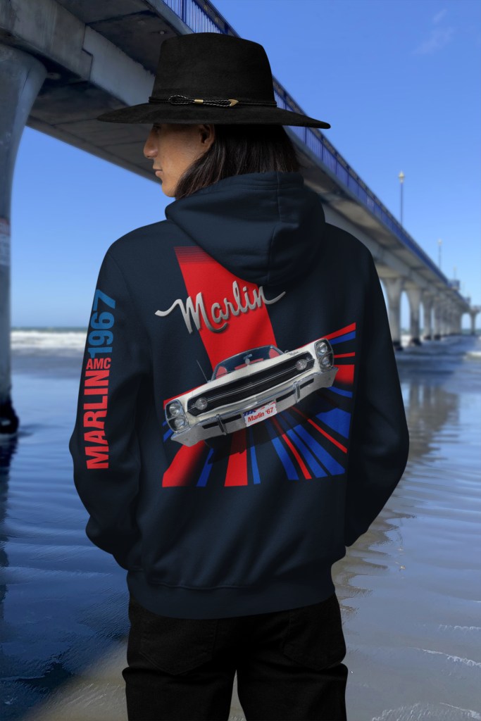 Back view of a man in navy blue AMC Marlin 1967 printed hoodie standing by New Brighton Pier with clear blue sky.