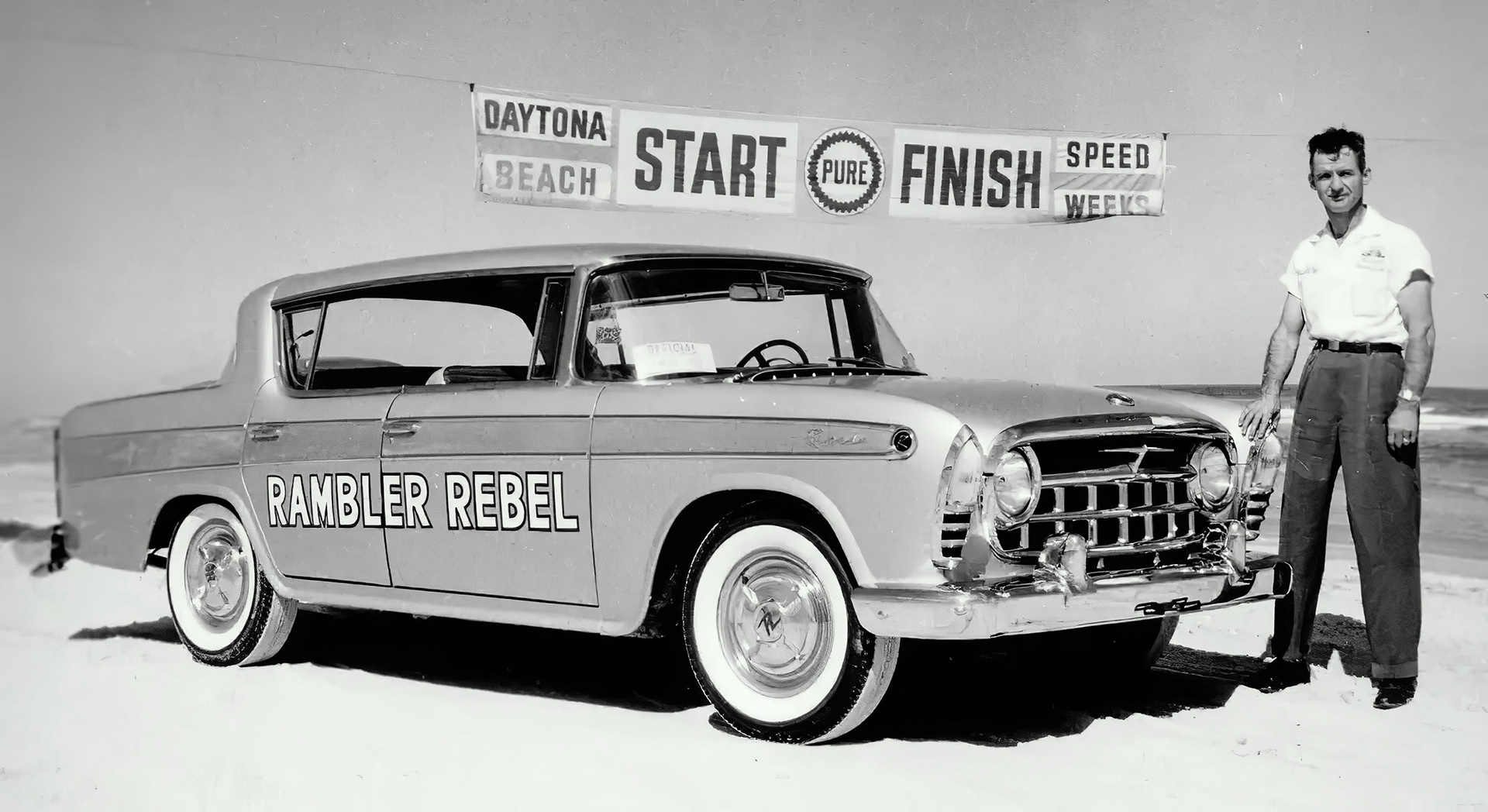 Black-and-white 1957 Rambler Rebel sedan at Daytona Beach Speed Week, showcasing its speed and unique design.