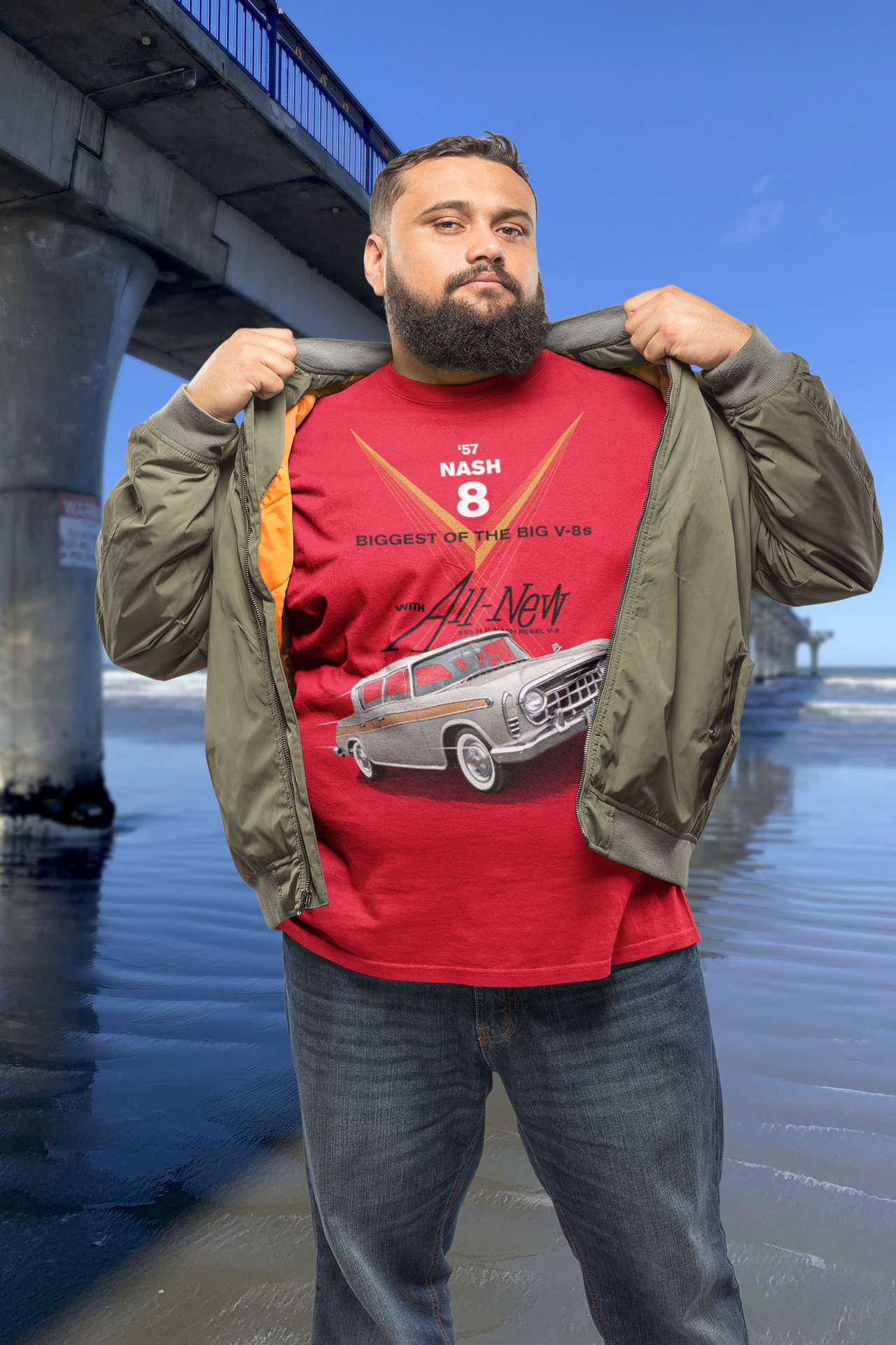 Man wearing a red 1957 Rambler t-shirt standing beside New Brighton Pier, celebrating the Rambler Rebel’s legacy.
