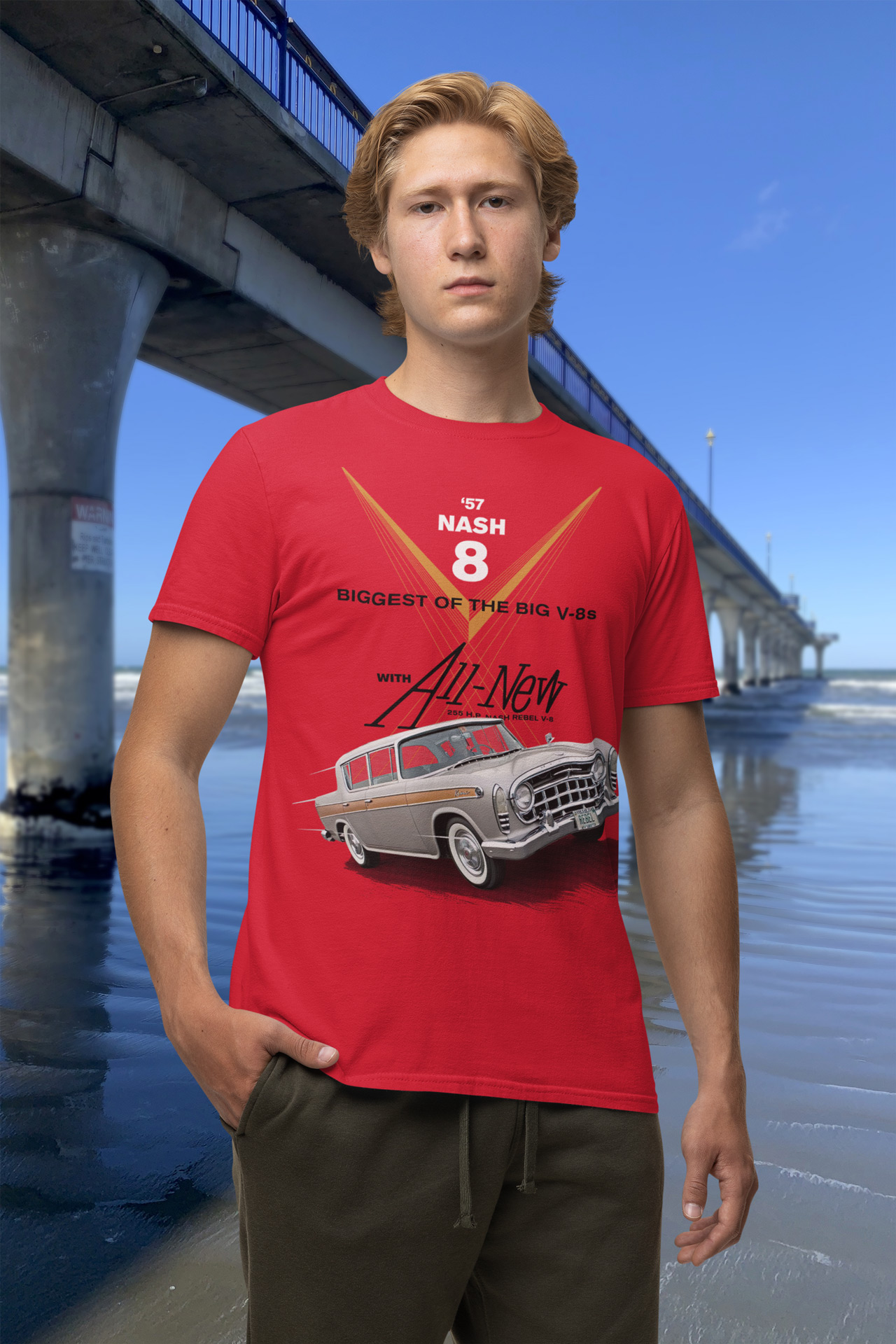 Young man in a red 1957 Rambler Rebel t-shirt standing beside New Brighton Pier.