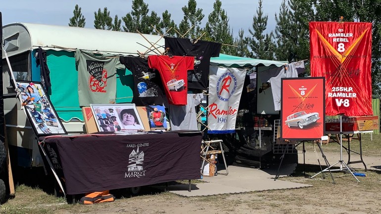 Photo of Daryl's stall at the 2024 McLeans Island swap meet, displaying re-created Rambler banners and t-shirts with classic car designs.