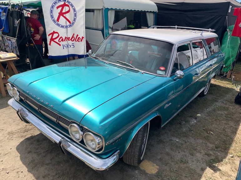 High front three-quarter view of a restored 1965 Rambler Classic 770 Countryman station wagon with a re-created Rambler dealer banner, shot at McLeans Island swap meet.